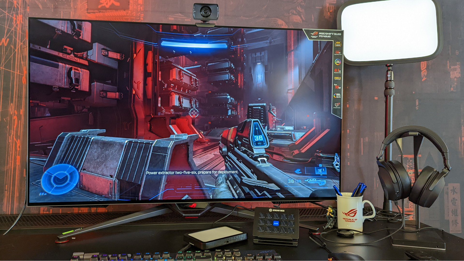 The Asus ROG Swift OLED PG42UQ gaming monitor, sat on a desk surrounded by various other periperhals